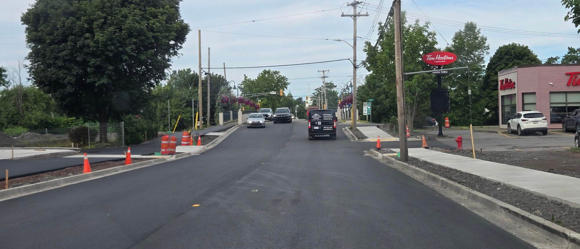 Image looking west along the east section of Main Street in Antigonish Nova Scotia, showing a fresh top of asphalt in a construction zone